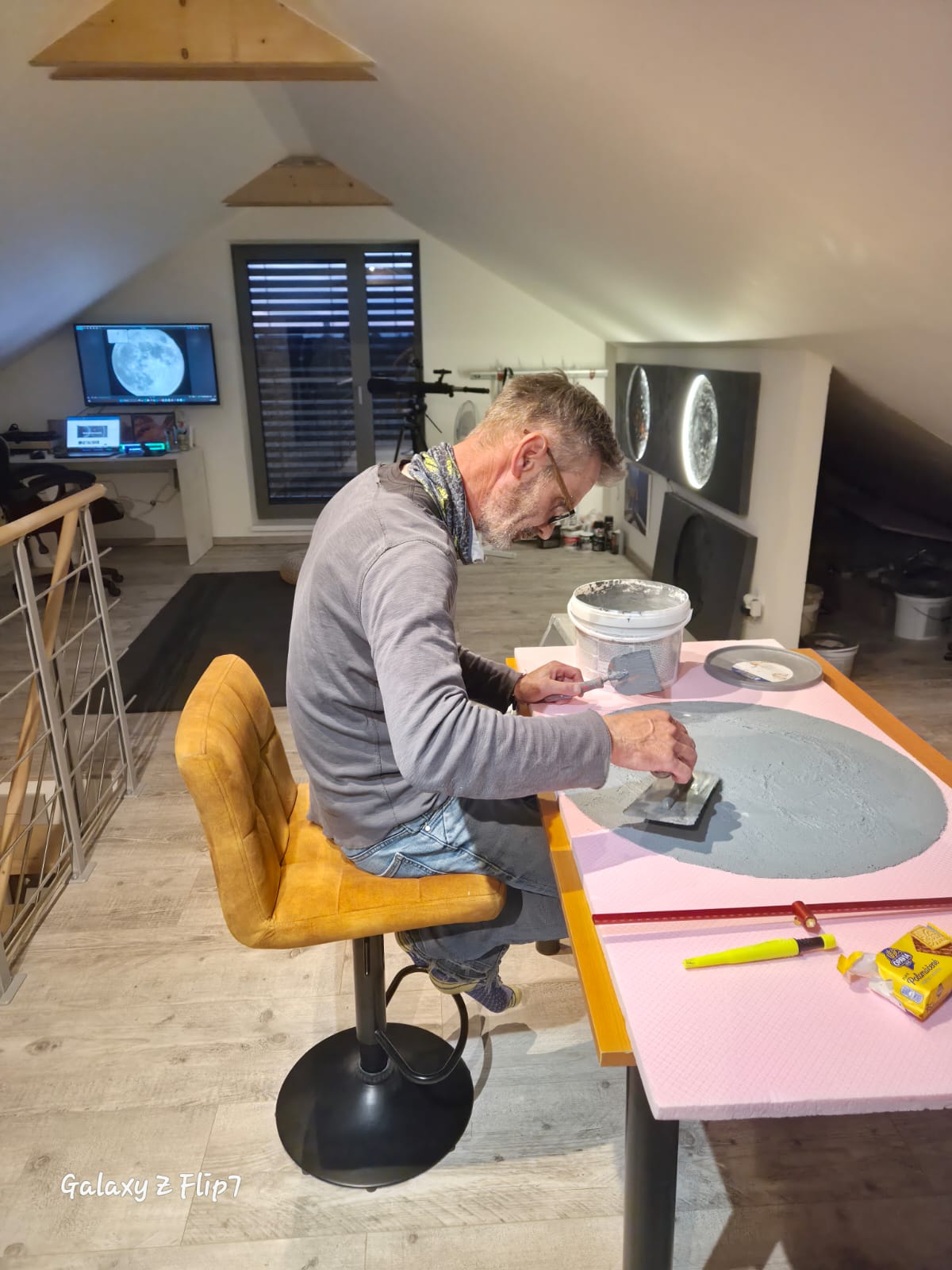 The creator of Project X hand-sculpts a textured space-inspired artwork in the studio, shaping the surface of a planet.